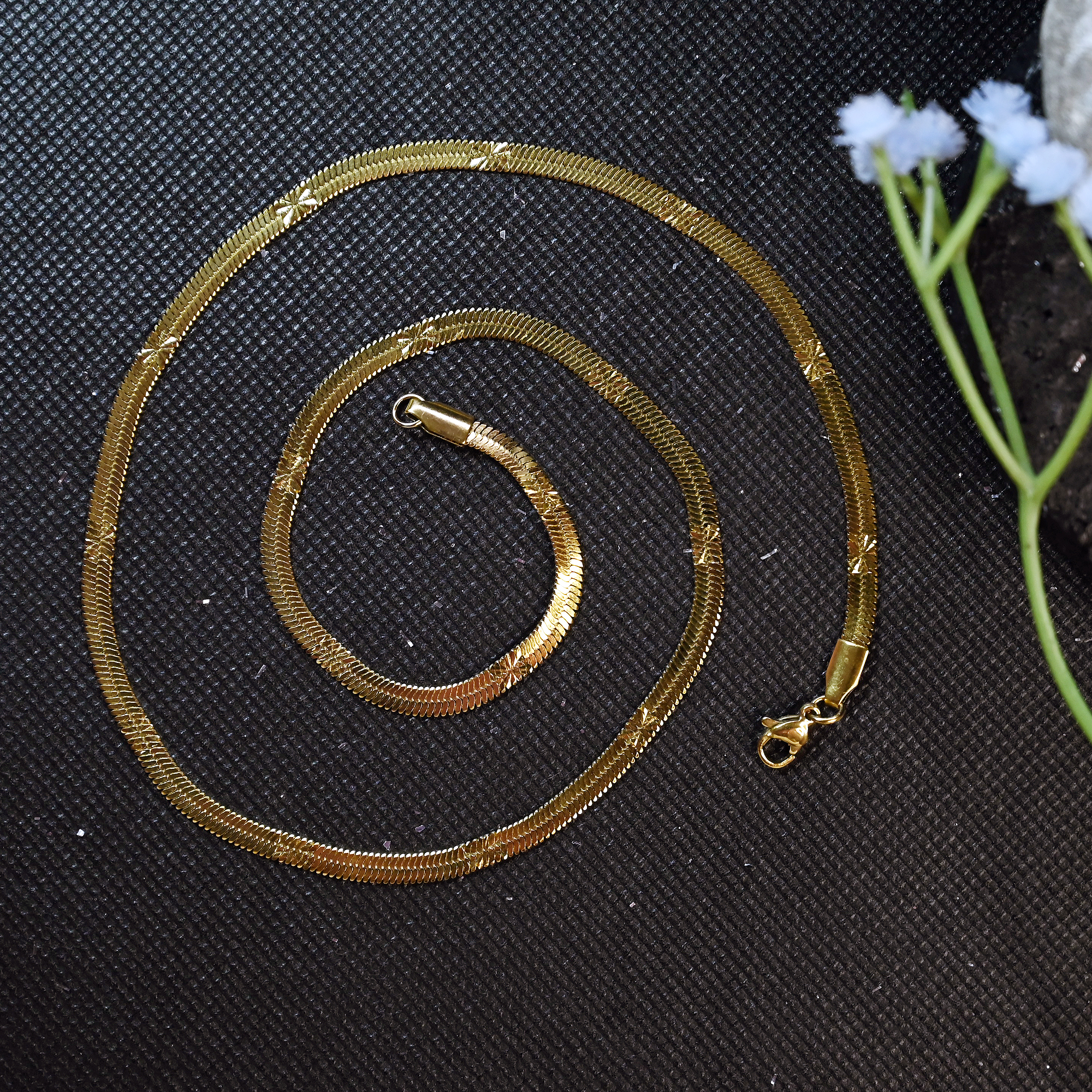 Flat snake gold necklace with embossed star detail design.