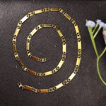 Close-up of gold stainless steel biscuit necklace for men.