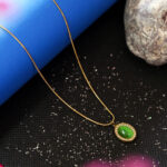 Women's gold snake chain necklace with green gemstone.