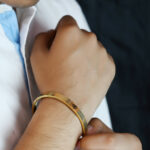 Gold plated Om kada bracelet with textured grid design.