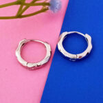 Close-up of hammered silver geometric huggie earrings.